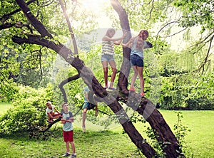 Happy kids climbing up tree in summer park