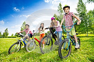 Happy kids in colorful bike helmets holding bikes