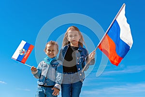 Happy kids, cute girls with Russia flag against a clear blue sky