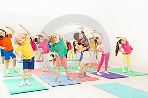 Happy kids doing side bending exercises in gym