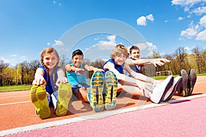 Happy kids doing stretching exercises on a stadium
