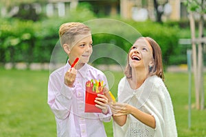 Happy kids eating fresh vegetables in nature - smiling children sharing colorful bio peppers sliced in form of french fries