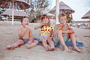 Happy kids eating ice cream on the sandy beach