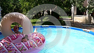 Happy kids enjoy swimming pool games in donu floats on sunny summer day, water play.