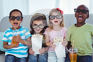 Happy kids enjoying popcorn and drinks while sitting