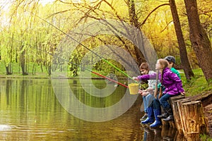 Happy kids fishing together near beautiful pond