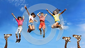 Happy kids group jump higher than head of giraffes