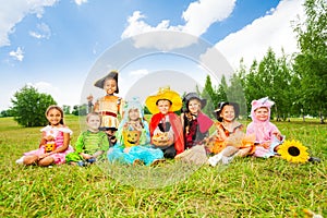 Happy kids in Halloween costumes sit on grass