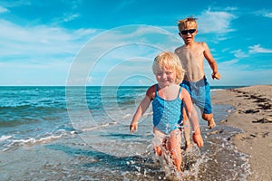 happy kids have fun on beach, boy and girl play at sea