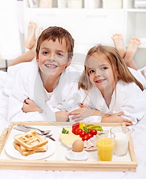 Happy kids having breakfast in bed