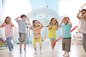 Happy kids having fun dancing indoors in a sunny room at day care or entertainment center