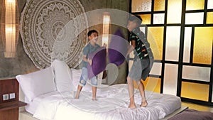 Happy kids having fun with pillows on bed. Asian brothers siblings pillow fighting at home