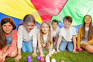 Happy kids hiding under colorful parachute outdoor
