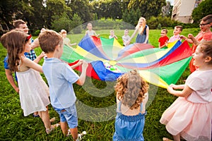 Happy kids holding parachute during funny game photo