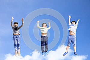Happy kids jumping and gesturing against blue sky