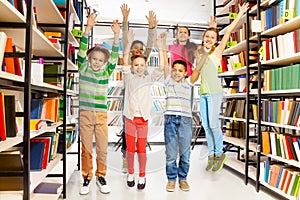 Happy kids jumping with hands up in the library