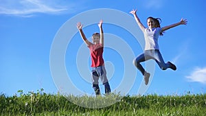 Happy kids jumping together on green grass hill against blue sky