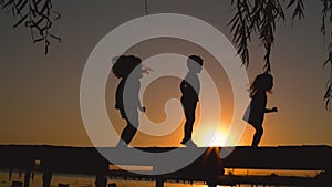 Happy kids jumping together during sunset in the park, silhouettes