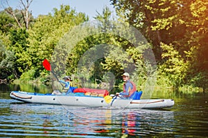 Happy kids kayaking on the river on a sunny day during summer vacation