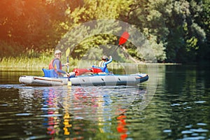 Happy kids kayaking on the river on a sunny day during summer vacation