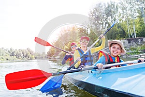 Happy kids kayaking on the river on a sunny day during summer vacation