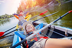 Happy kids kayaking on the river on a sunny day during summer vacation