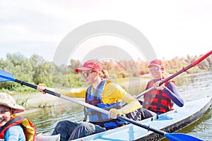 Happy kids kayaking on the river on a sunny day during summer vacation