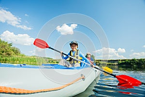 Happy kids kayaking on the river on a sunny day during summer vacation