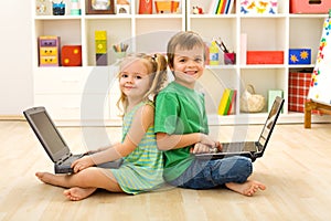 Happy kids with laptops sitting on the floor photo