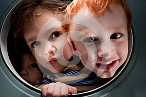 Happy kids looking through window porthole photo