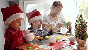 Happy kids with mother cutting out Christmas garlands from colorful paper. Winter holidays, family time together, kids
