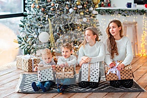 Happy kids near the Christmas tree with the present boxes