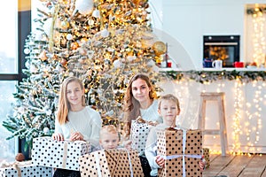 Happy kids near the Christmas tree with the present boxes