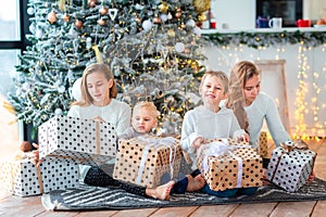 Happy kids near the Christmas tree with the present boxes