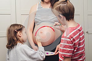 Happy kids painting pregnant belly their mother. Baby birth expecting time and belly painting