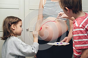 Happy kids painting pregnant belly their mother. Baby birth expecting time and belly painting