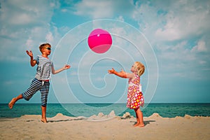 Kids play with ball on beach, boy and girl have fun at sea