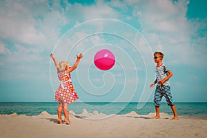 Kids play with ball on beach, boy and girl have fun at sea