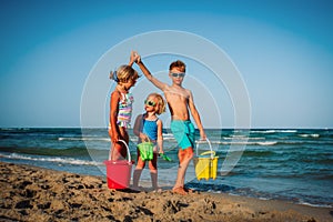 Happy kids play on beach, boy and girls have fun at sea