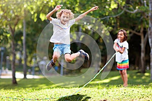 Happy kids play outdoor. Children skipping rope