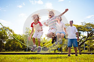 Happy kids play outdoor. Children skipping rope