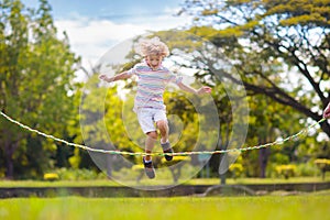 Happy kids play outdoor. Children skipping rope