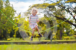 Happy kids play outdoor. Children skipping rope