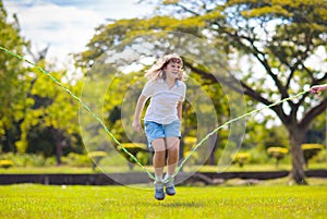 Happy kids play outdoor. Children skipping rope