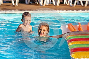 Happy kids playing in blue water of swimming pool.