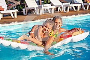 Happy kids playing in blue water of swimming pool.