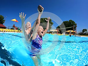 Happy Kids Playing Catch in Swimming Pool on Summer Day