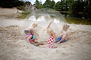 Happy Kids Playing Outside in the Sand at the Beach by the Swimming Lake