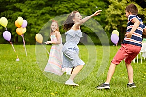 Happy kids playing tag game at birthday party