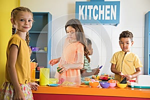 Happy kids playing with a toy kitchen in children room.